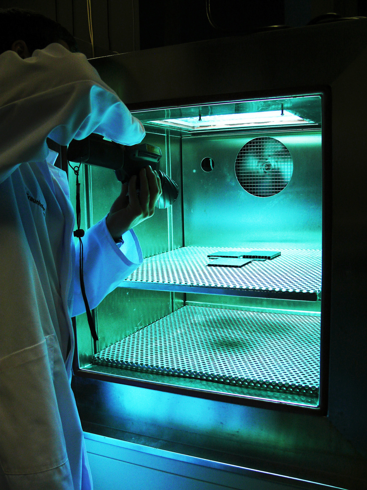 Scientists at Fraunhofer ISE using a thermal imaging camera to check the surface temperature of a polymer sample during UV aging in a climatic chamber.